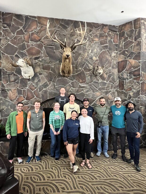 Team Bond in front of a large stone fireplace with mounted taxidermy animals