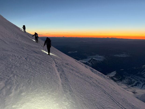 Climbers traverse the upper mountain on Rainier at sunrise