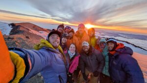 A team stands at the summit of Mount Rainier with the sunrise in the background
